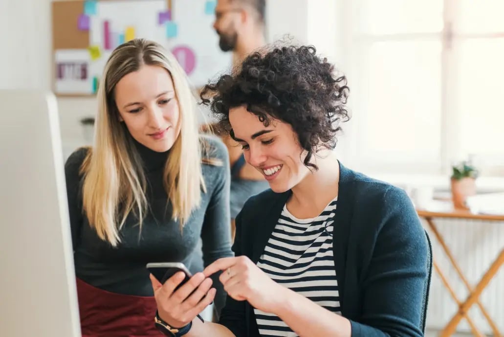 two-female-employees-looking-at-a-phone