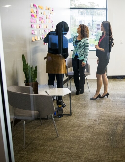 Three people looking at a wall of sticky notes