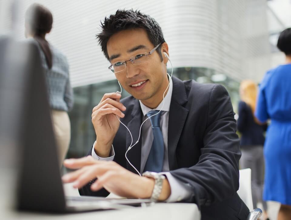 man typing whilst wearing earphones