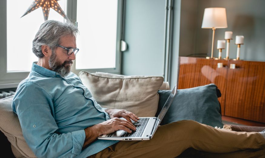 man typing on laptop keyboard on a chair